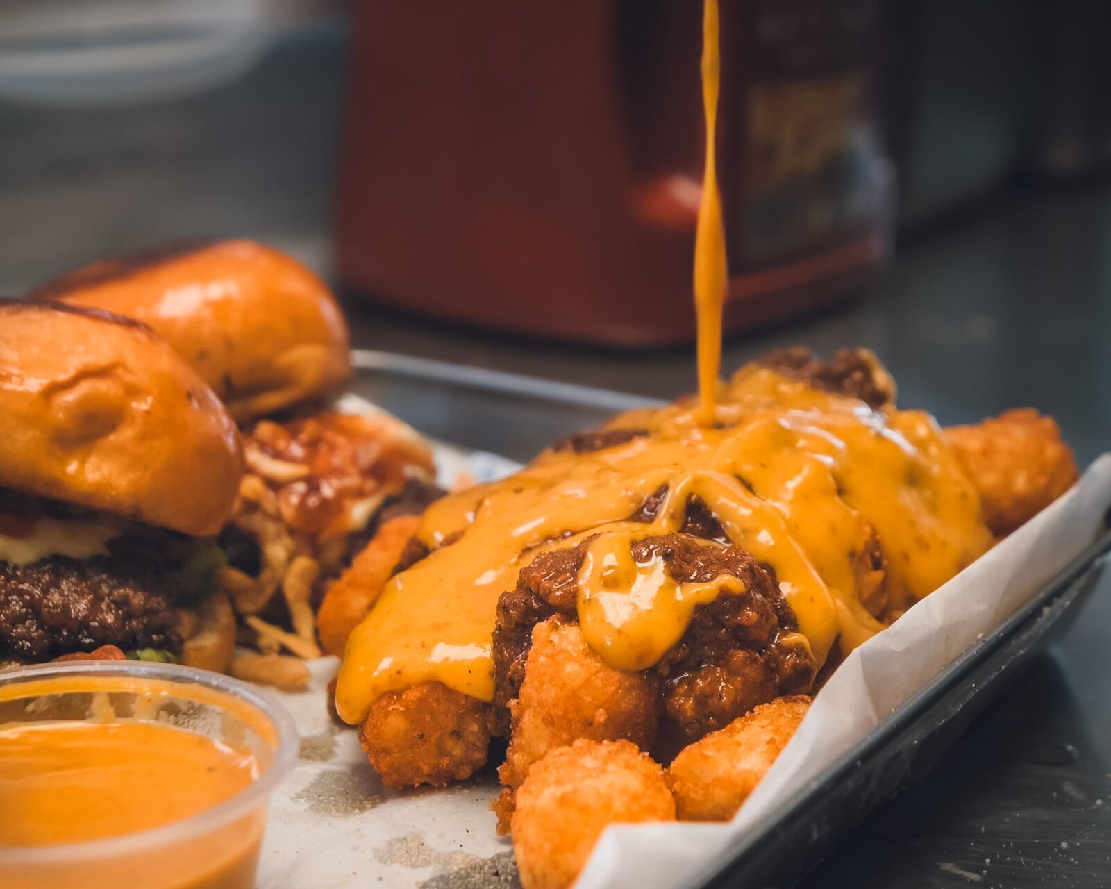 Gold sauce being poured over loaded fries